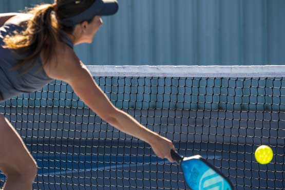 woman playing pickleball about to hit ball